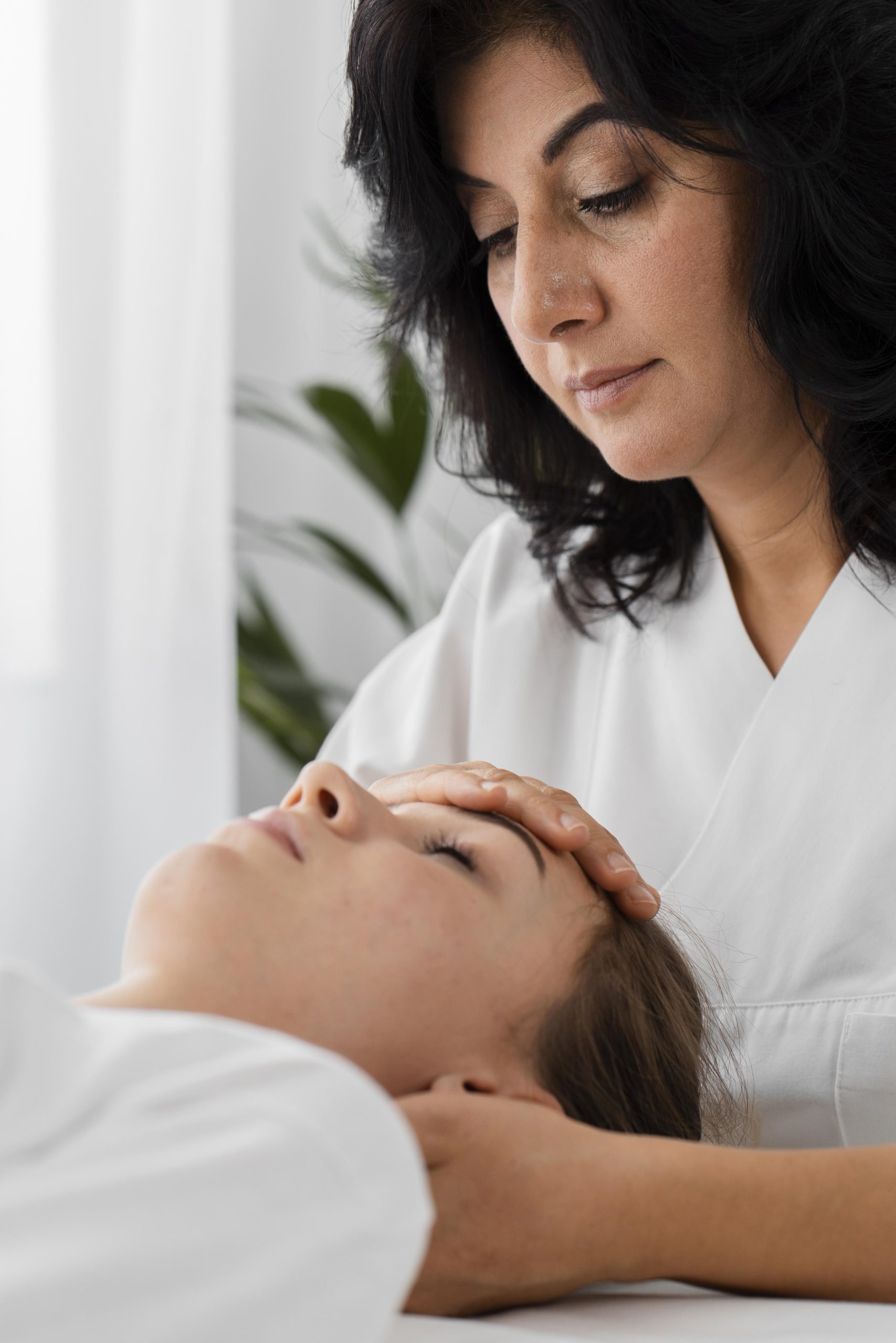 osteopathist treating female patient by massaging her face
